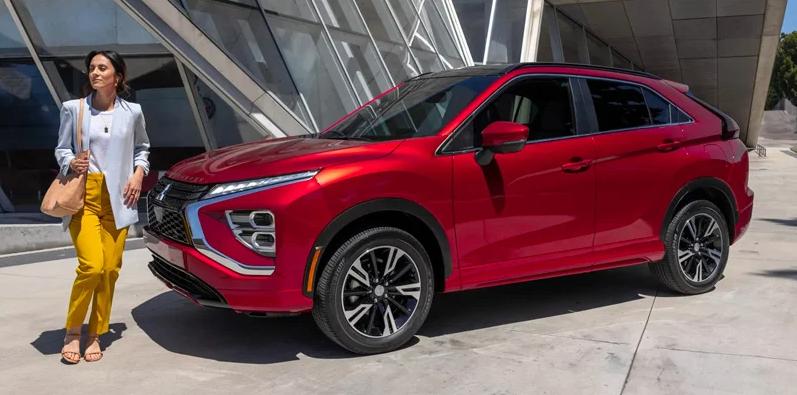 A woman walking around a red 2024 Mitsubishi Eclipse Cross.