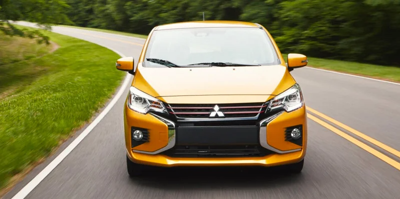 A Yellow 2024 Mitsubishi Mirage driving down the road.