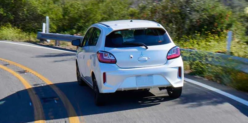 A white 2024 Mitsubishi Mirage driving down the road.
